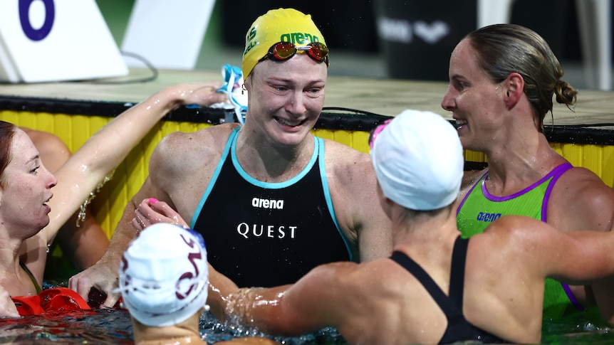Cate Campbell is surrounded by other swimmers in the pool after her race