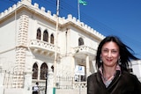Maltese investigative journalist Daphne Caruana Galizia poses outside a white building with a blue sky background.