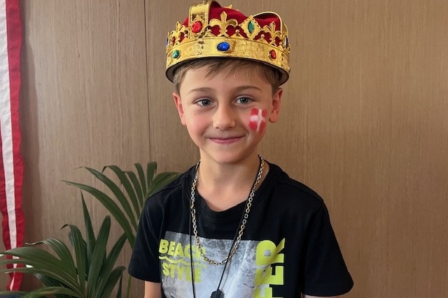 A young boy wearing a toy crown and with a Danish flag painted on his cheek