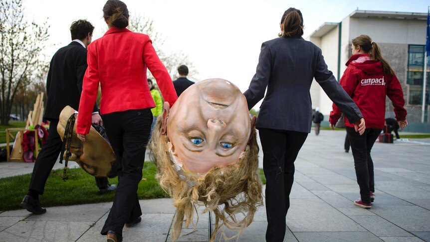 Activists carry a giant head of German Chancellor Angela Merkel before a demonstration in Berlin.