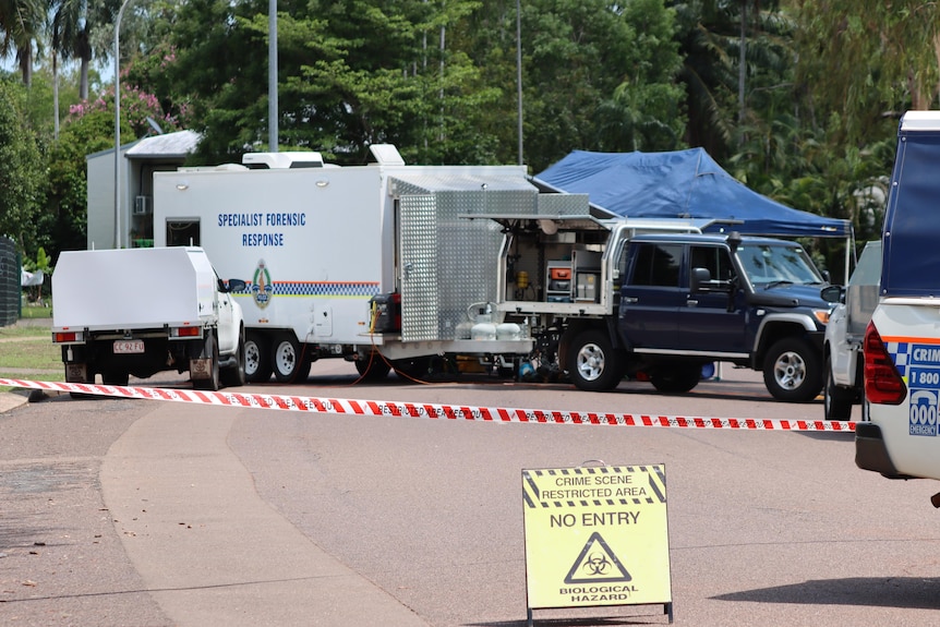 Several NT Police vehicles parked in a suburban street, with police tape in the foreground.