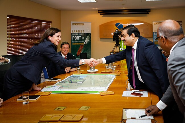 Queensland Premier Annastacia Palaszczuk shakes hands across a table with Gautam Adani.