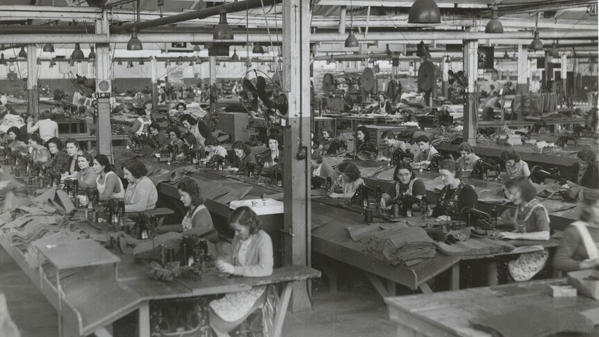 A historic photo showing a factory full of women sitting at sewing machines