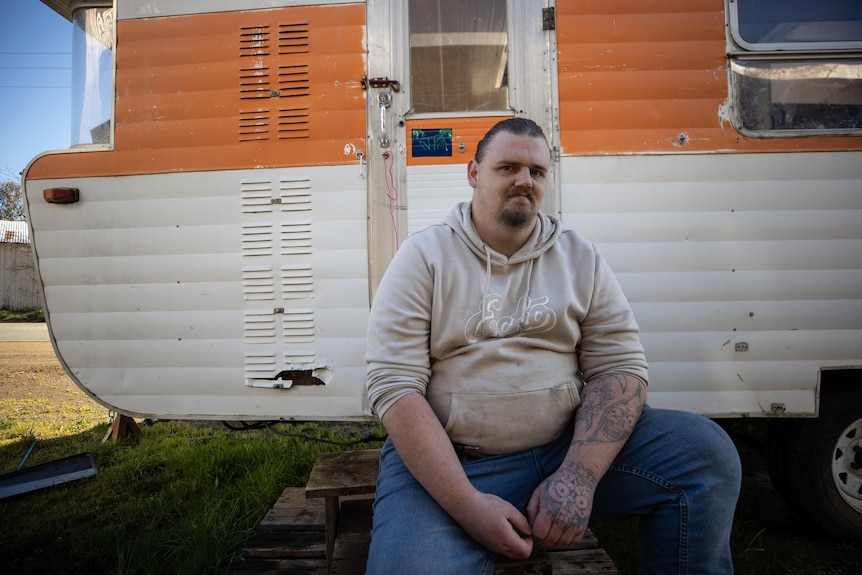 Alex Carter sitting in front of a caravan.