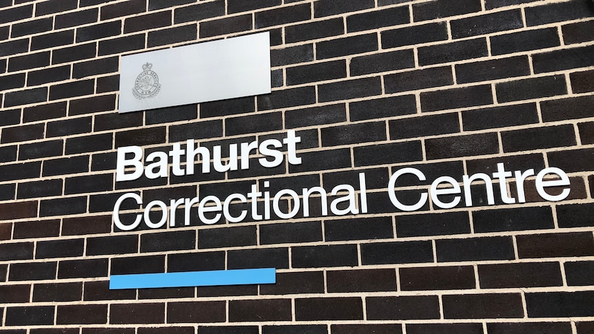 Metal lettering spells out Bathurst Correctional Centre on a black brick and white mortar wall