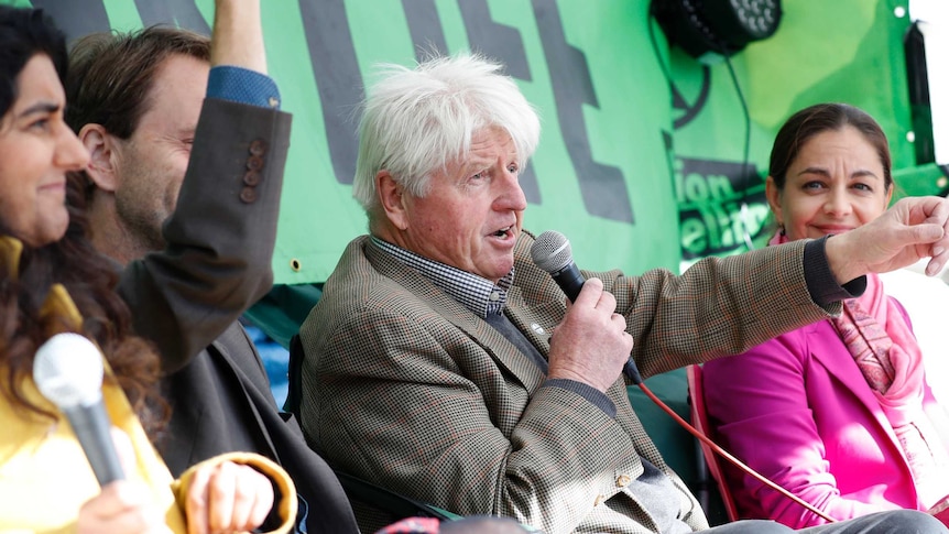 Stanley Johnson joins several other cheering and smiling climate activists on stage at Extinction Rebellion