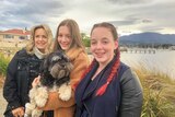 Allana, Isabella and Indiana Corbin stand on a footpath with their dog on Hobart's eastern shore.