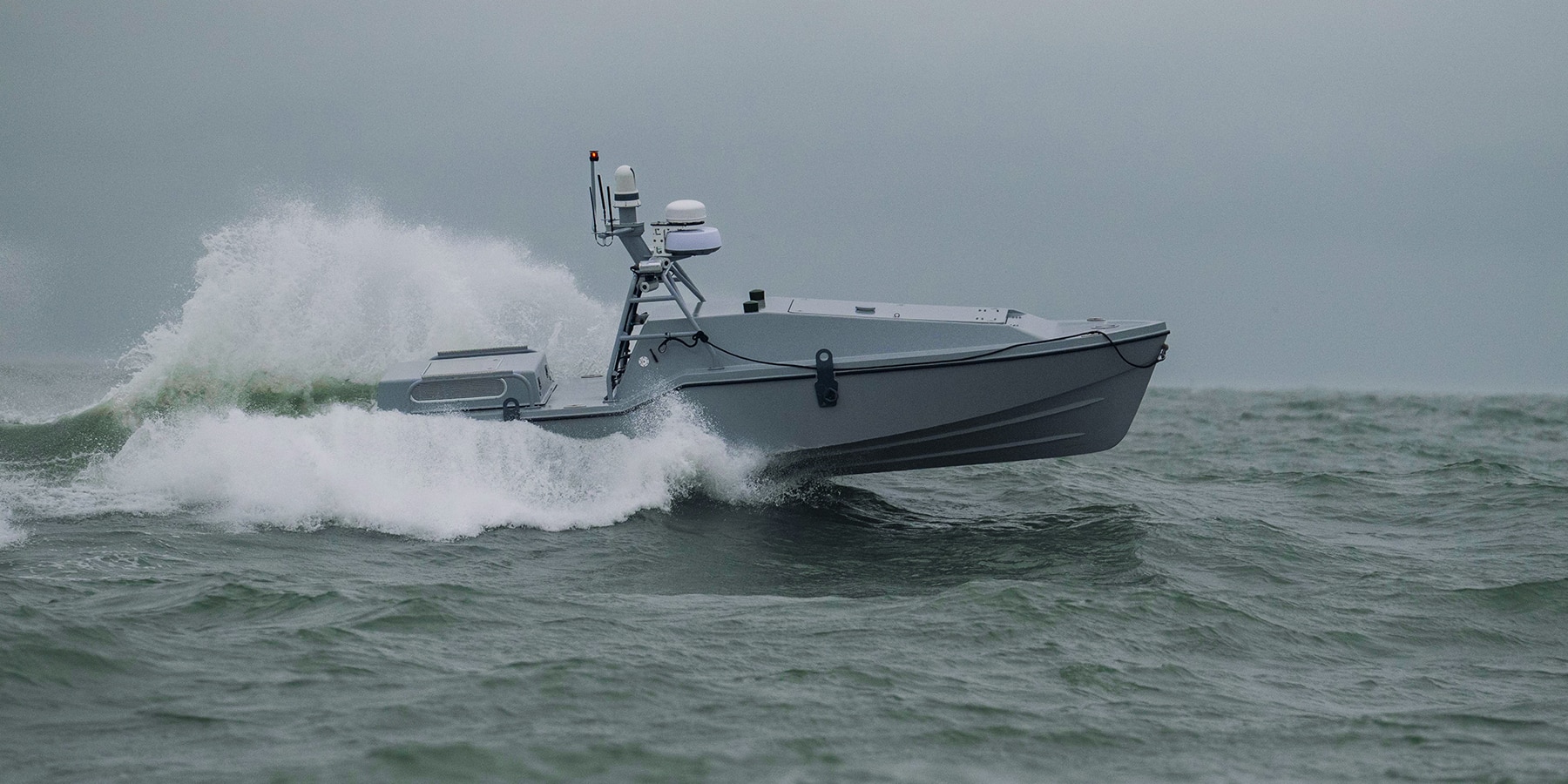 An unmanned military boat speeds across the ocean.