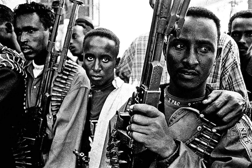 Somali pirates holding guns stare into Sebastian Rich's camera