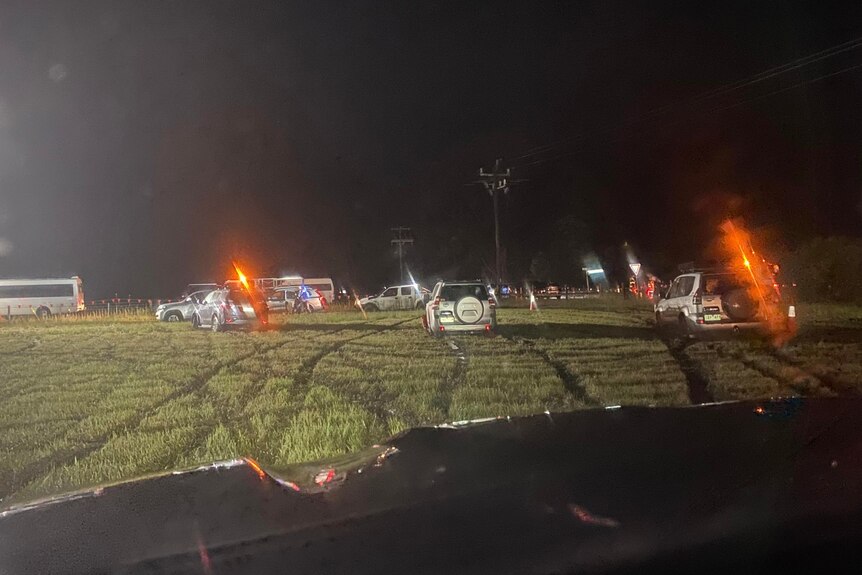Cars bogged in a field at night.