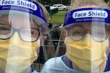 Two nurses wearing face shields and other protective equipment.