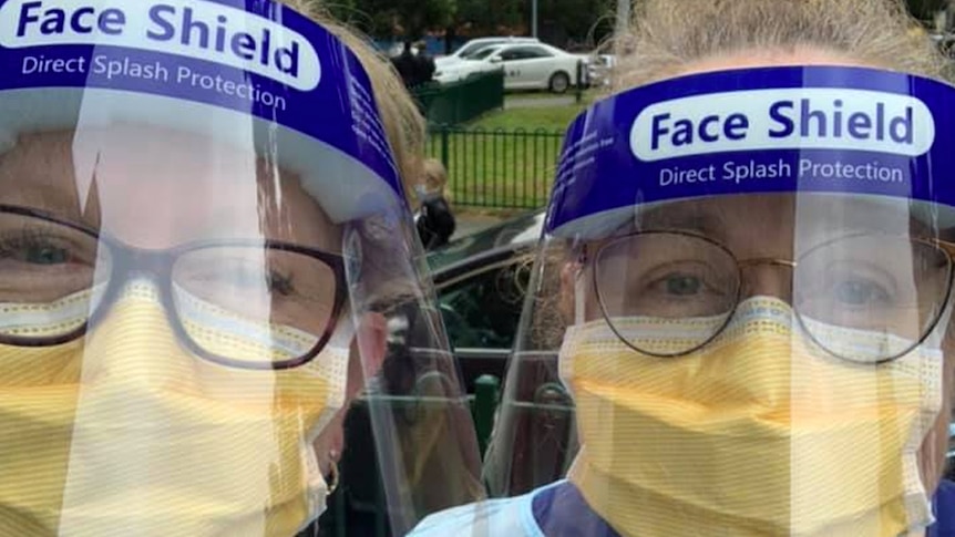 Two nurses wearing face shields and other protective equipment.