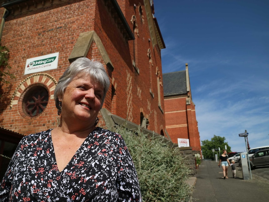 A woman stands in front of an old church looking to her left