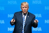 Trump is seen at an NRA event pointing at audience.