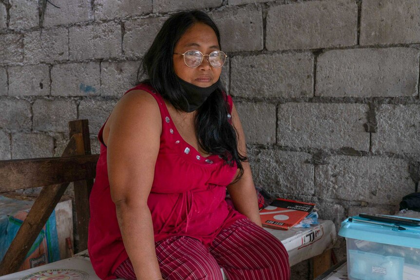 Ligaya Sambayon sitting on a bench looking pensive with face mask pulled down below her chin