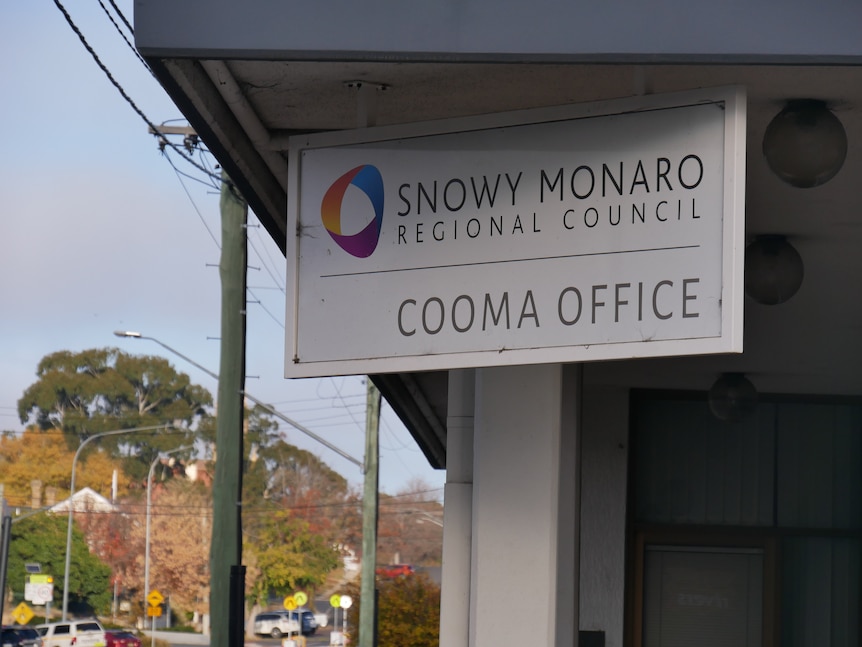 A sign reading "Snowy Monaro Regional Council Cooma Office" hanging above a shopfront in a country town.
