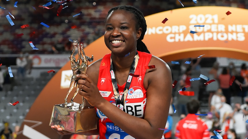 Sam Wallace holds the Super Netball trophy as streamers red and blue fly around her head