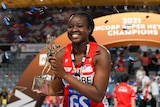 Sam Wallace holds the Super Netball trophy as streamers red and blue fly around her head