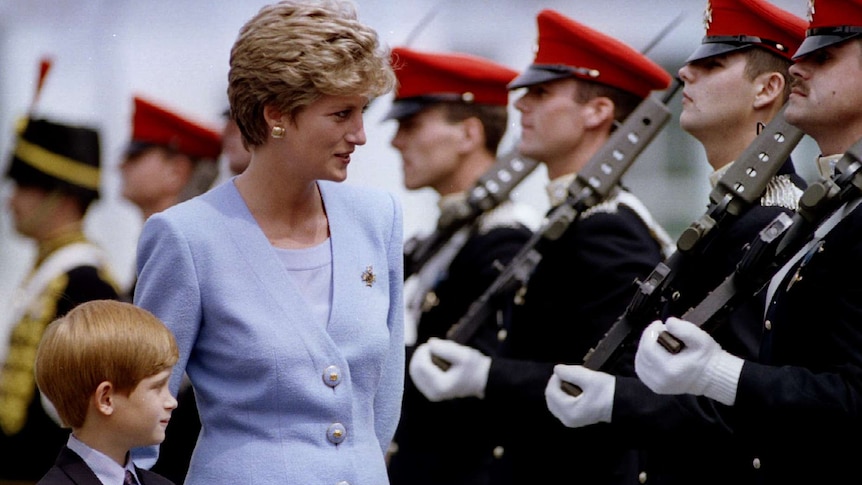 You view Princess Diana in a tailored, lavender blazer and matching top, walking alongside troops in red hats with Prince Harry.