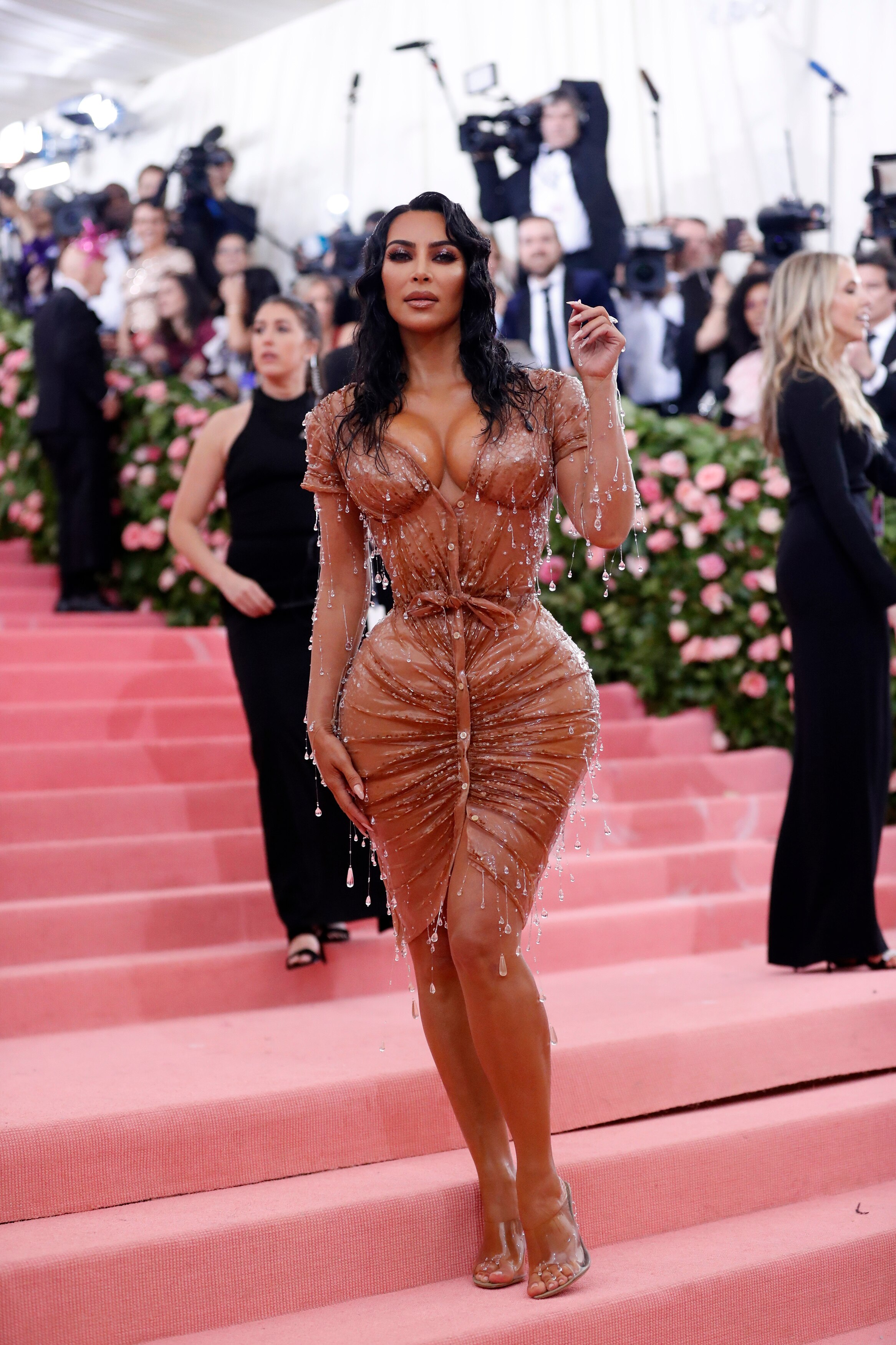 Kim Kardashian wearing a blush latex dress with glass beads hanging of it looking like raindrops. He hair is styled to look wet