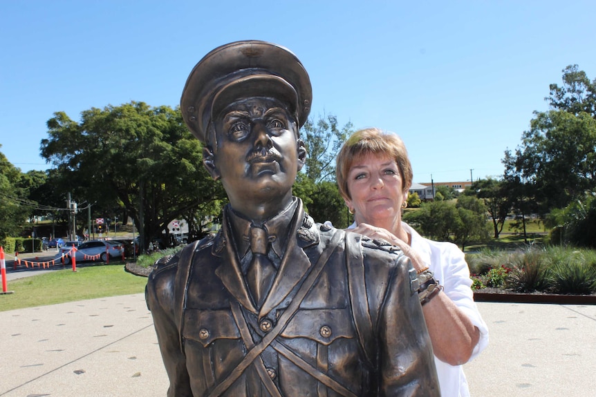 A lady stands behind a bronze sculpture of a WW1 soldier