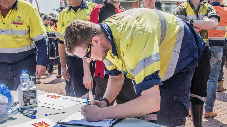 A mine worker signs a petition against the Government's increase to the Gold Royalty.