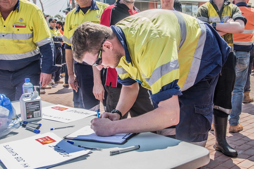 A mine worker signs a petition against the Government's increase to the Gold Royalty.