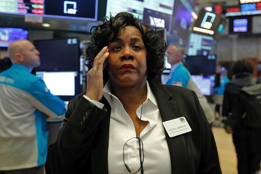 A female trader looks concerned on the floor of the New York Stock Exchange.
