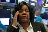 A female trader looks concerned on the floor of the New York Stock Exchange.