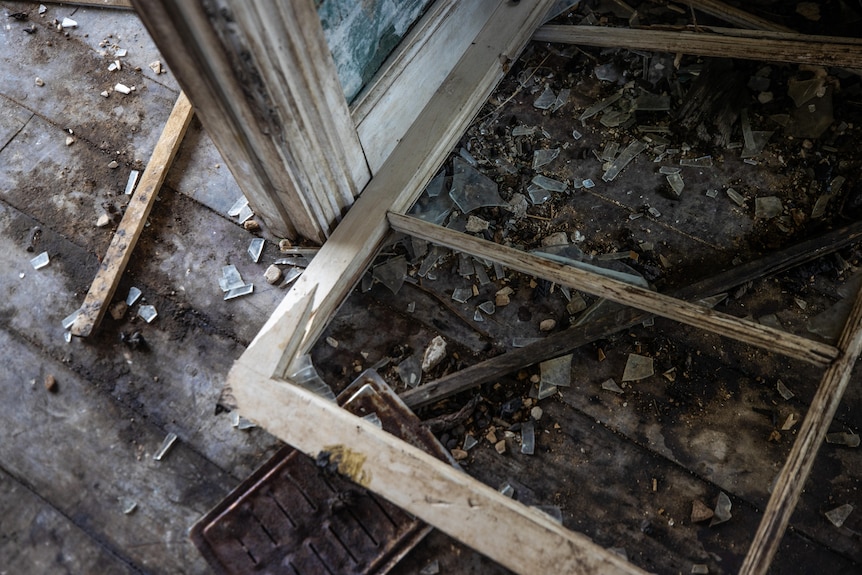 Broken window and shattered glass on floor.