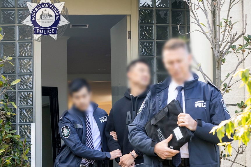 一名男子在一幢房子前被两名警察带走