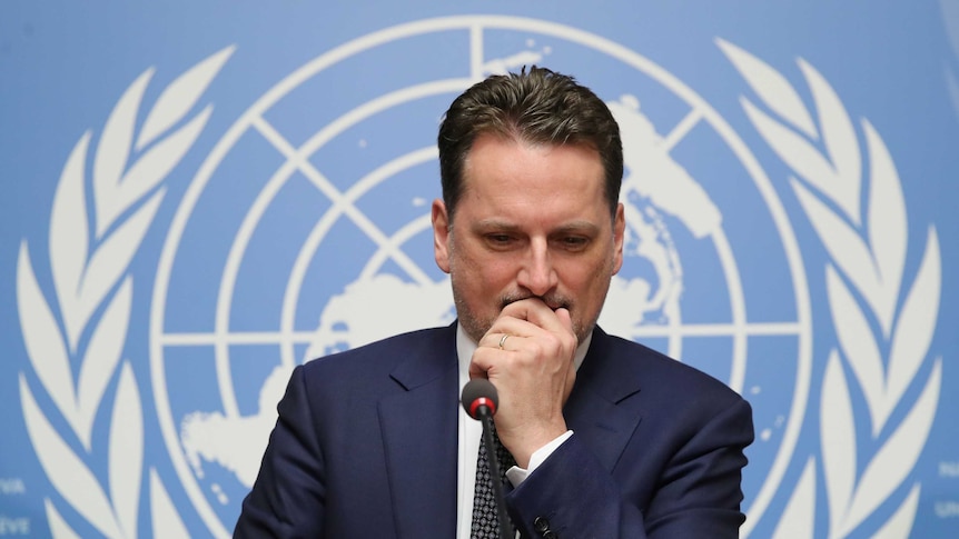 Pierre Krahenbuhl is pictured mid-shot, sitting in front of a large light blue backdrop with the UN logo.