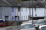 Police in forensic suits enter one of a line of similar houses in an English town.