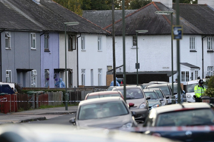 Police in forensic suits enter one of a line of similar houses in an English town.