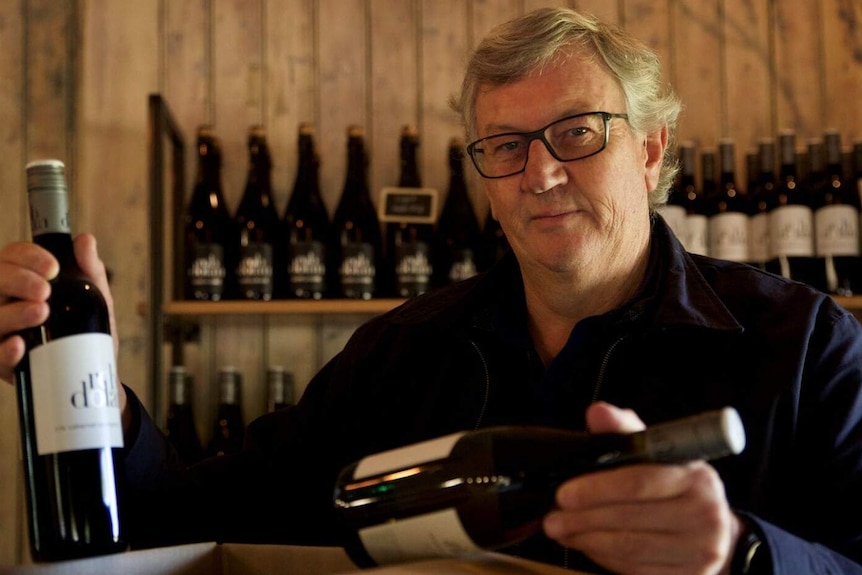 Rob Dolan faces the camera as he packs bottles of wine into a box for delivery.