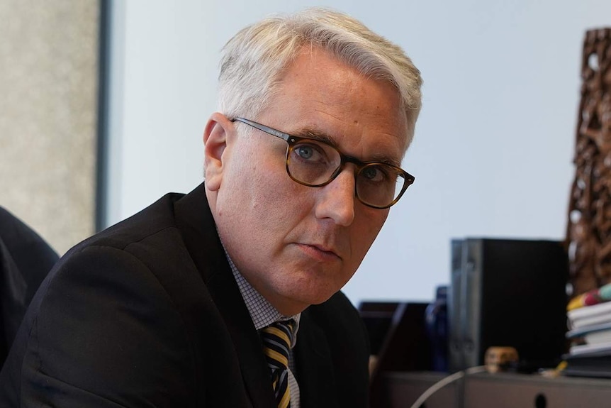 A man with grey hair at a desk.