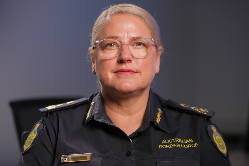 Female Australian Border Force officer with glasses, in uniform with her hair tied back.