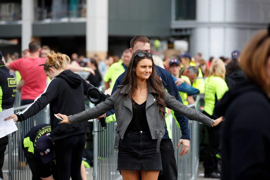 Two young female concert-goers spread their arms out for security guards.