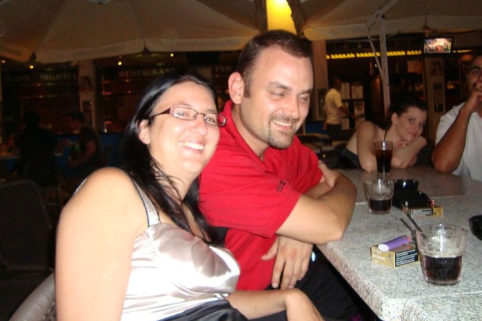 Man and woman sit at bar with drinks and smokes laughing
