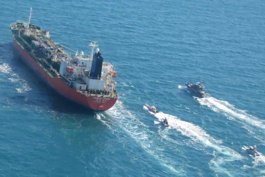 Large red tanker ship followed by smaller vessels