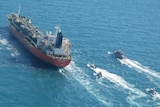 Large red tanker ship followed by smaller vessels