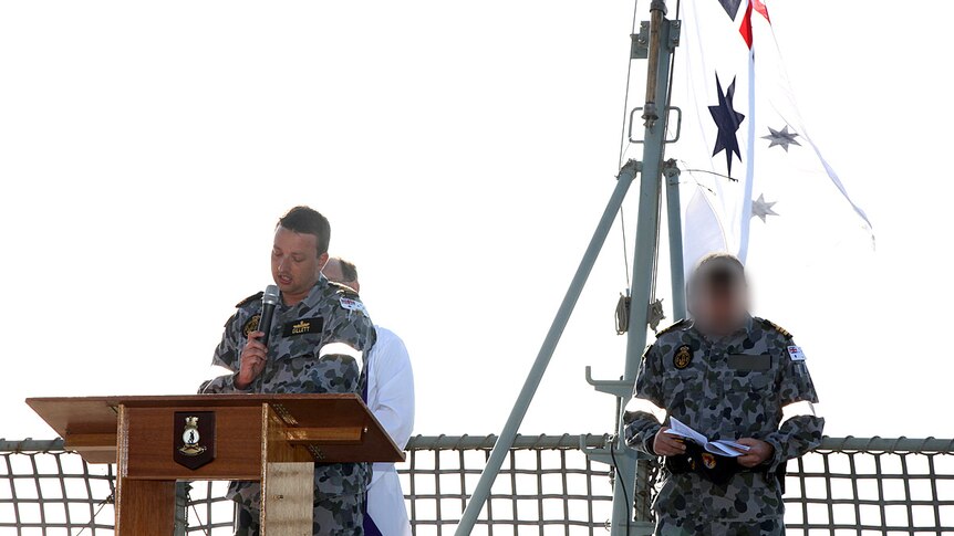 Man in uniform on a ship at a podium.