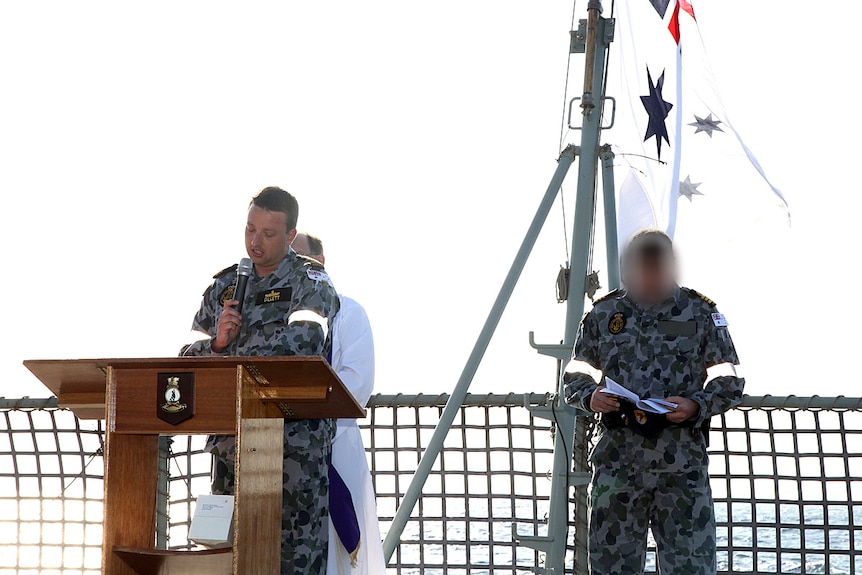Man in uniform on a ship at a podium.