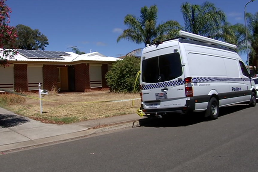 A police van and station wagon in front of a house with roller shutters