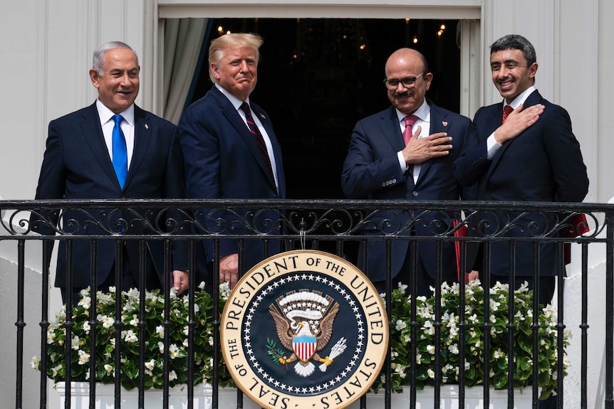 Donald Trump and Israel's PM look down proudly as the leaders of Bahrain and UAE hold their hands over their hearts.