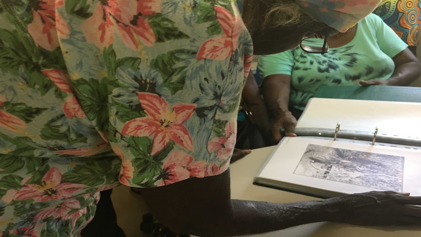 A woman examines historic images as part of the Returning Photos Project