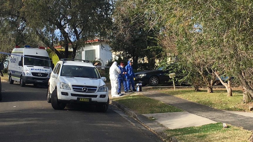 Police in special suits outside a suburban home.