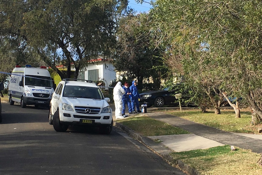 Police in special suits outside a suburban home.