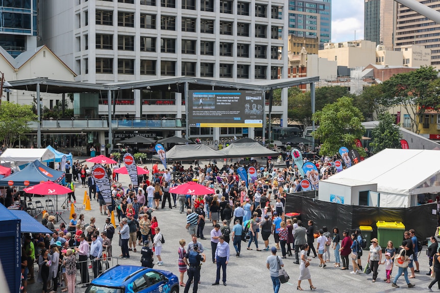 Crowds of people in a square lining up for an Ekka strawberry sundae