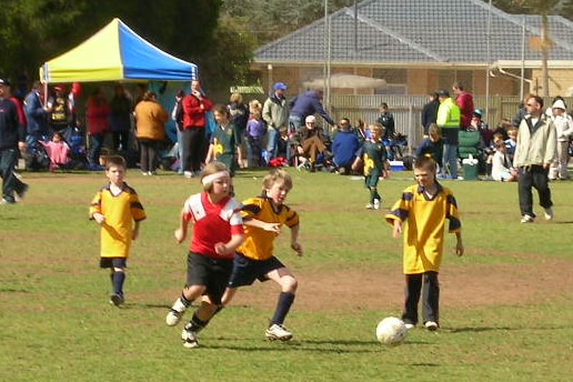 A young girl runs across a soccer pitch, as three boys on the opposing team watch on.